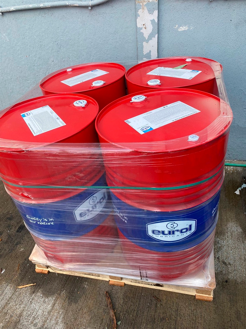 Tambores de óleo lubrificante industrial azuis e vermelhos empilhados em exterior